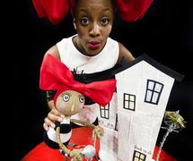 Actress Alicia McKenzie with puppet character Alice on her bicycle, in <em>Ring a Ding Ding</em> (2011) by Oily Cart (London, UK), direction: Tim Webb, design: Claire de Loon, puppet construction: Sue Dacre, with wirework by Mogothi, puppeteers: Alicia McKenzie, Griff Fender. Direct manipulation puppetry. Photo courtesy of Collection: Oily Cart. Photo: Patrick Baldwin