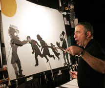 Paul Zaloom behind the screen performing <em>The Mother of All Enemies</em> (2003), an adaptation of traditional <em>Karagöz</em> shadow theatre by American puppeteer and political satirist Paul Zaloom (b.1951), concept, design, construction and direction: Paul Zaloom; design/construction: Lynn Jeffries; puppeteer: Paul Zaloom