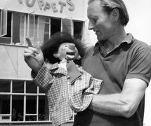 Bob Pelham avec une marionnette Pelham, un « <em>Vent</em> », devant l'usine Pelham Puppets. Une marionnette de ventriloque (en anglais, <em>vent figure</em>). Photo: Pelham Puppets Ltd (Photo archive)
