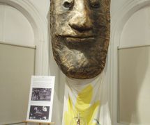 Red Bishop, finger puppet of Robert Anton (in front of Bread and Puppet Theater giant head), at the “With Or Without Strings” exhibit that surveyed late 20th Century New York City puppetry (Flushing Town Hall, New York, 2006). The exhibit also included several other Anton puppets and his tiny finger puppets from <em>7 Deadly Sins</em>. Photo: Stephen Kaplin